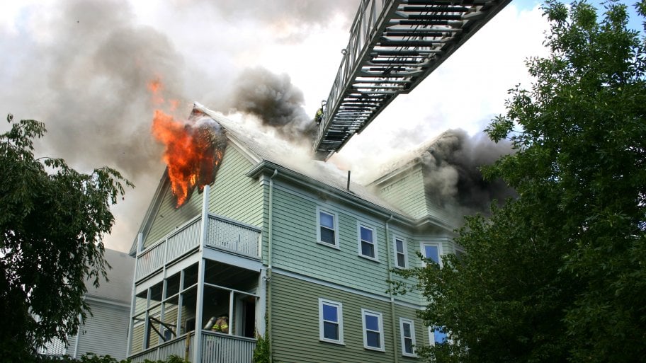 2-story house on fire with fire ladder extended to it